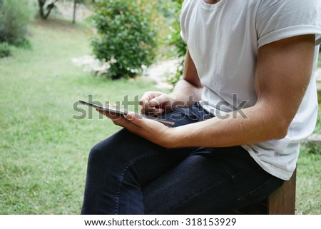 Man using digital tablet in the park. Man holding the tablet on a background of trees