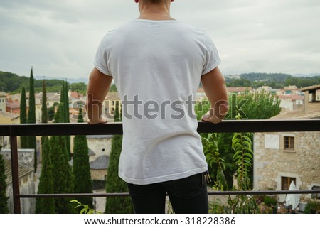 Man wearing white t-shirt on a city background(Back view)