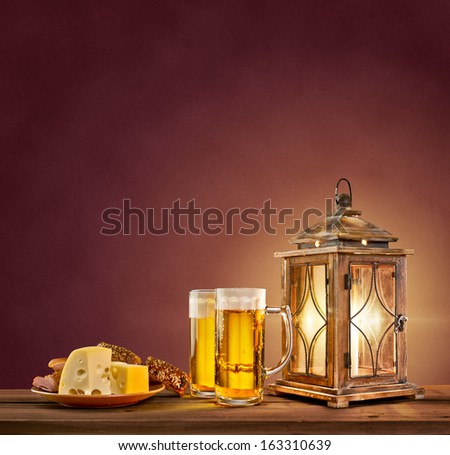 old lantern with beer, cheese and bread on vintage background