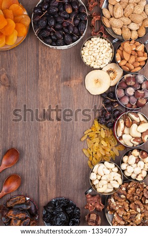 Frame of variety of fruits and nuts on a dark wooden surface