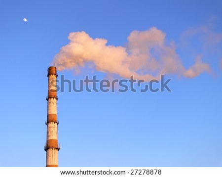 Smoking factory pipe in the sunset over the blue sky