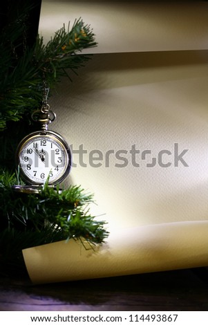New Year decoration. Vintage pocket watch hanging near fir tree against blank scroll
