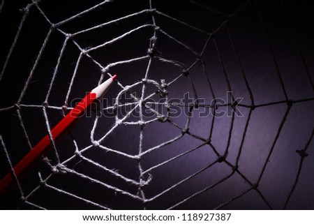 Web design concept. Red pencil in rope web on dark background
