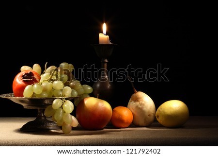 Vintage still life with fruits in bowl near lighting candle