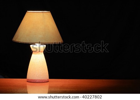 Nice luminous table lamp with yellow shade standing on wooden table