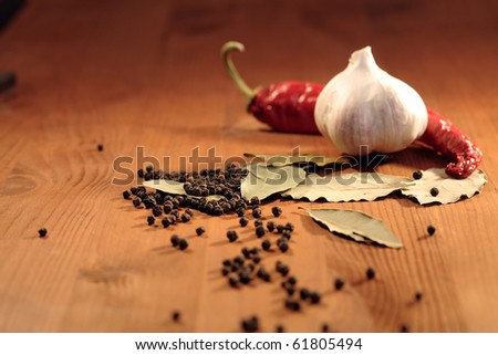 Bay leaves, head of garlic and peppercorns on wooden background