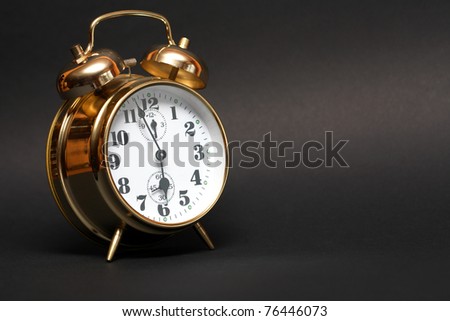 Nice golden alarm clock on dark background with copy space