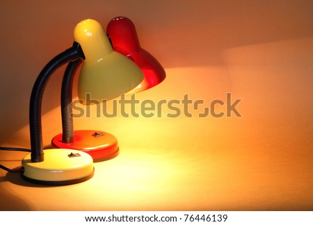 Pair of modern luminous desk lamps on yellow background with copy space