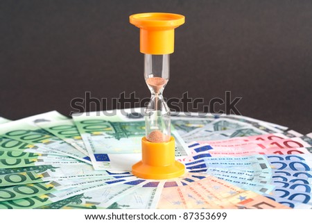 Time is money concept. Hourglass standing on european union currency background