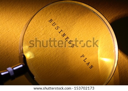 Business concept. Magnifying glass on paper surface with BUSINESS PLAN inscription