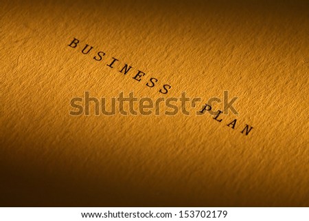 Business concept. Paper surface with BUSINESS PLAN inscription under beam of light