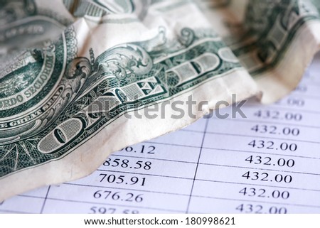 Business concept. Closeup of crumpled one dollar bank note on paper table with digits