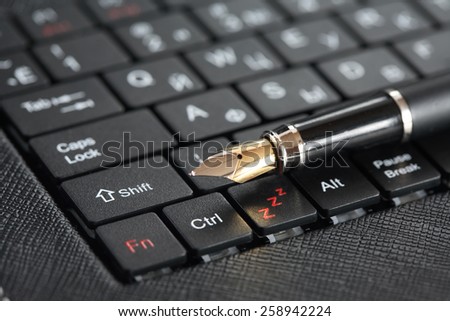 Modern literature. Closeup of fountain pen on black computer keyboard