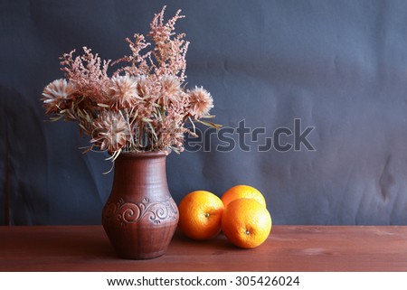 Nice bouquet of dry flowers in ceramic vase and freshness oranges fruits