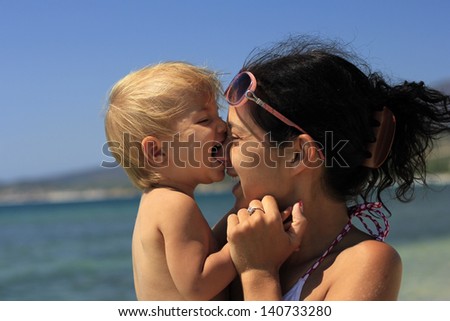 Baby biting her mother\'s nose