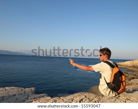 Looking into the horizon - young man holding map and pointing horizon.
