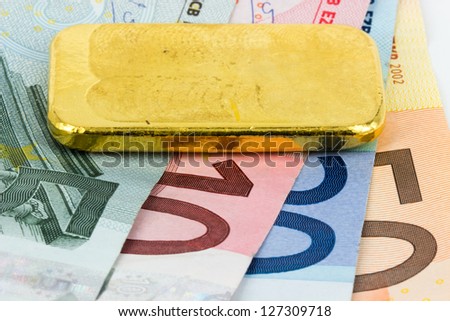 Gold bar standing on euro bank notes