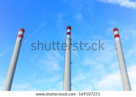 Three tall white and red chimney, no smoke, on blue cloudy sky. landscape, nobody