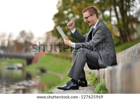 Young businessman receiving winning news on tablet computer