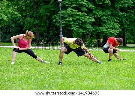Group of three young health athletes doing stretching exercise relaxing and warm up after jogging and running in park