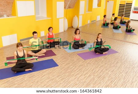 Aerobics pilates group with rubber bands in a row at fitness gym