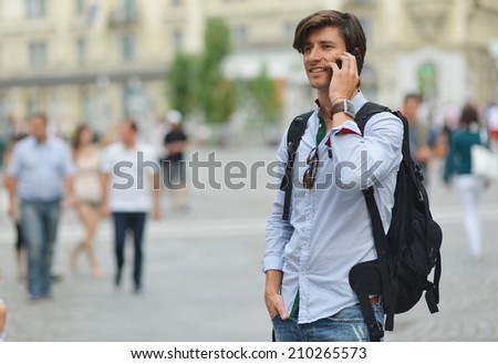 Student with the mobile smart phone walking, background is blurred city