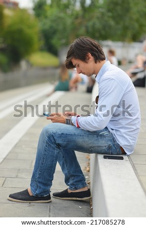 Young student reading on tablet computer in the city