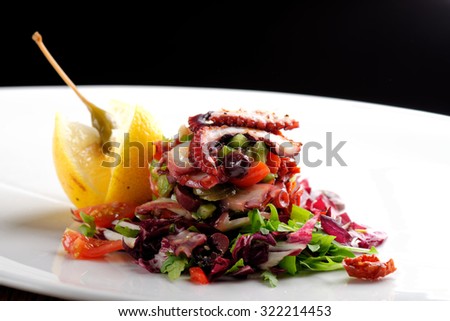 Fine dining octopus salad with lemon slice, tomato and lettuce