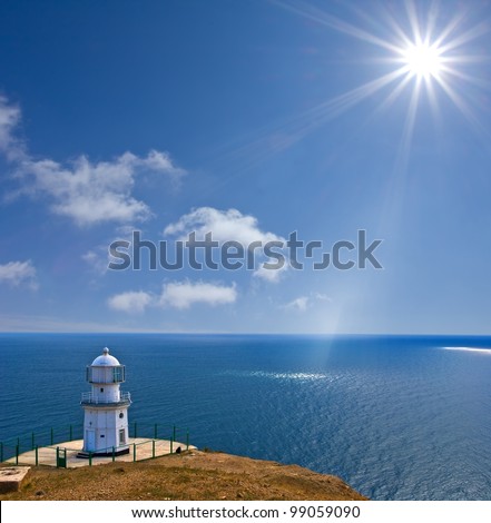 lighthouse on a sea coast under a sparkle sun