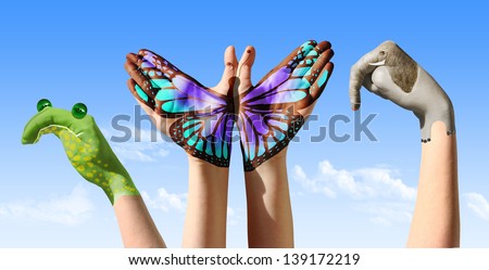 Child hands painted in colorful paints or tattoo with frog, butterfly, elephant.