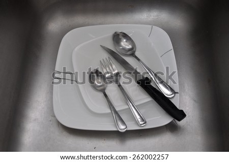 Knife, fork, spoon and plates in the sink