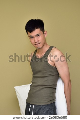 Thai man in undershirt with his pillow shows his playful thought before bed.