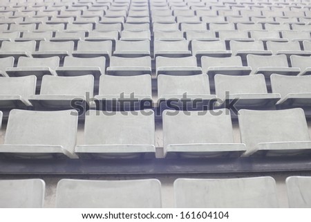 Empty plastic stadium seats in a row black and white
