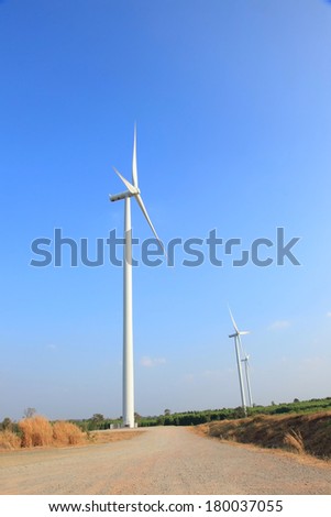 windmill turbine electric generator in field at the rural road.