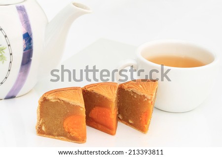 Festival Moon cake with nuts and yolk inside and hot tea in white cup - chinese dessert sweet food.