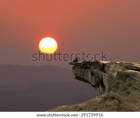 Dinosaur bird-shaped rock The orange sky and sun rises.