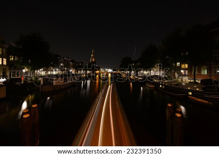 Night view on the Amsterdam canal at night with boat lighting trails in Holland