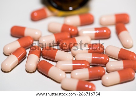 Prescription pill bottle spilling capsule pills on to surface
