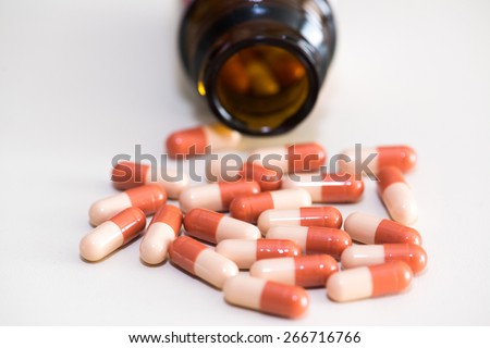 Prescription pill bottle spilling capsule pills on to surface