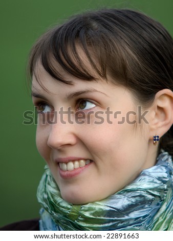 Face portrait of pretty smiling girl on green blurry background