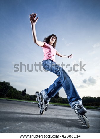 Wide-angle shot of a rollerblading girl performing \'compass\' element - little motion blur