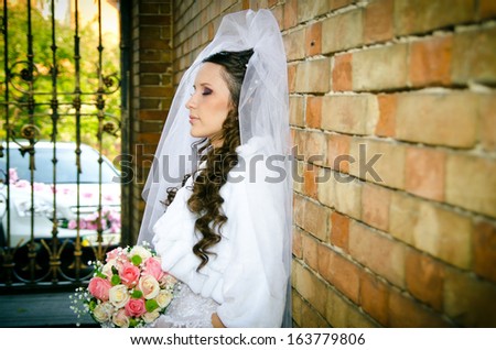 bride in a white dress near the wall of an old castle. gate, arch