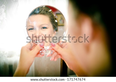 gentle bride looks in the mirror and smiling