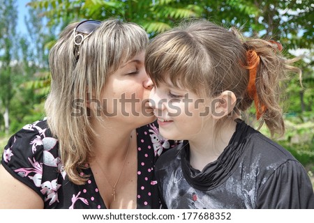 Portrait mother and daughter. mom kissing teen daughter