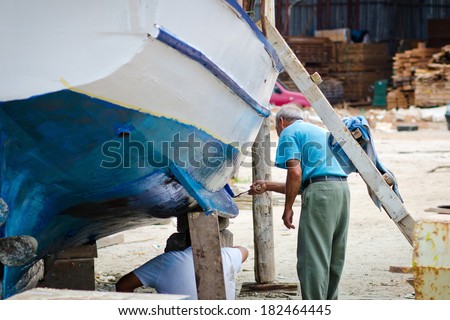 man running and boat paints. old port worker repairing a boat
