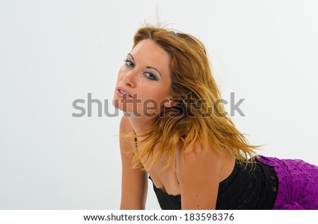 Tanned girl in a black tank top and a purple skirt posing in the studio, white background