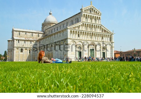 Tourists visit leaning tower in Pisa. Pisa, Italy. girl lying on the green grass