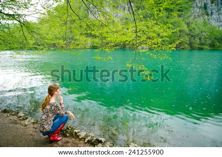 happy girl walking in the park. Dressed in a bright clothes and rubber boots. Plitvice Lakes, Croatia. rest on the bench
