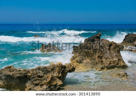 Waves crashing on rocks. blue waves, sand beach and blue sky. Greece, the island of Lefkada, Yialos Beach, Gialos