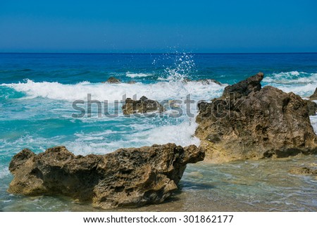 Waves crashing on rocks. blue waves, sand beach and blue sky. Greece, the island of Lefkada, Yialos Beach, Gialos
